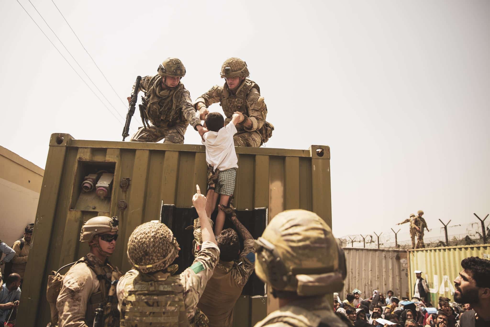 U.S. Marines assist a child during an evacuation at Hamid Karzai International Airport, Kabul, Afghanistan, Aug. 20, 2021. (U.S. Marine Corps photo by Staff Sgt. Victor Mancilla)