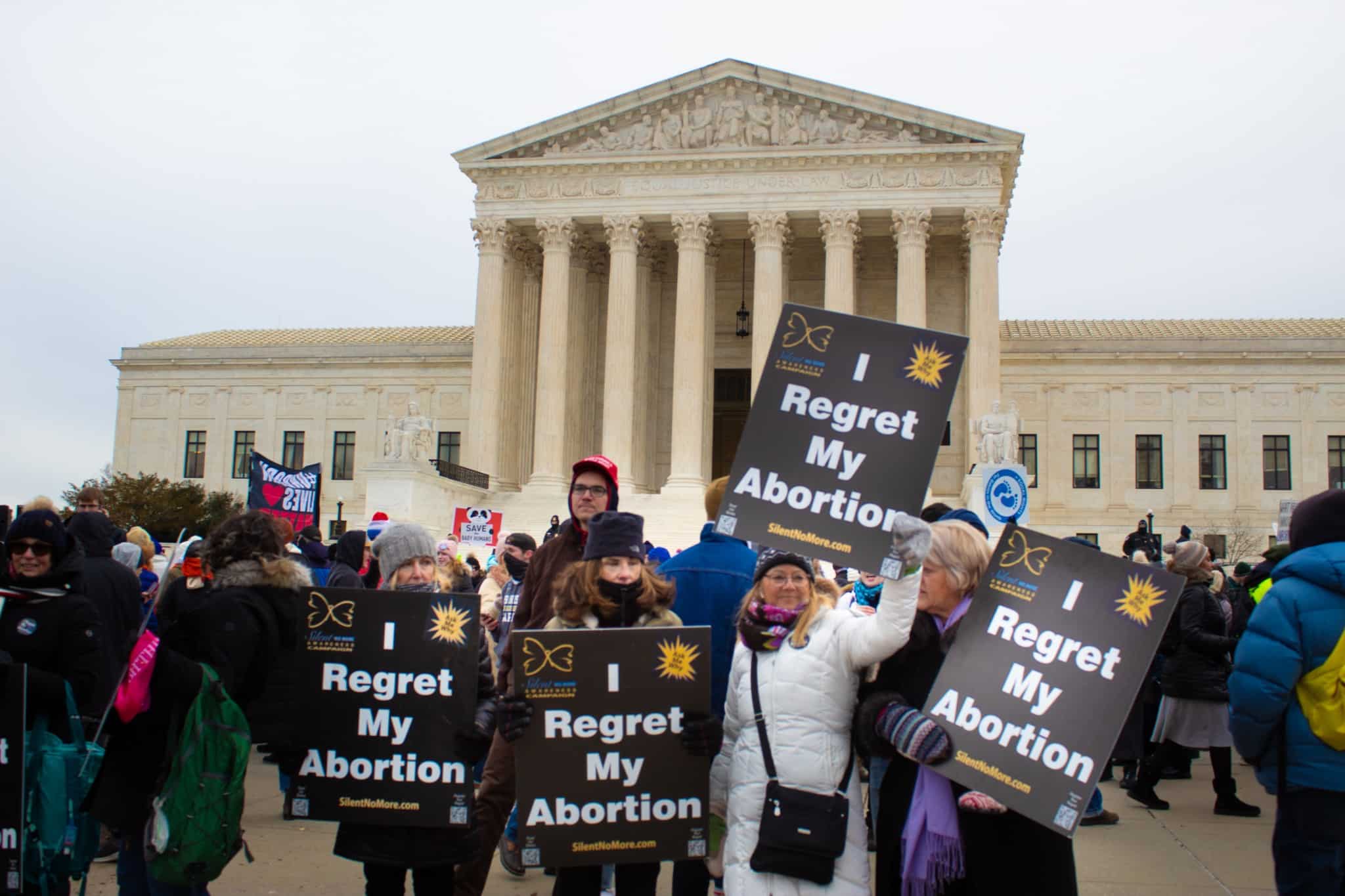 Women hold signs reading “I regret my abortion” in front of the Supreme Court on January 21, 2022. (The American Spectator)