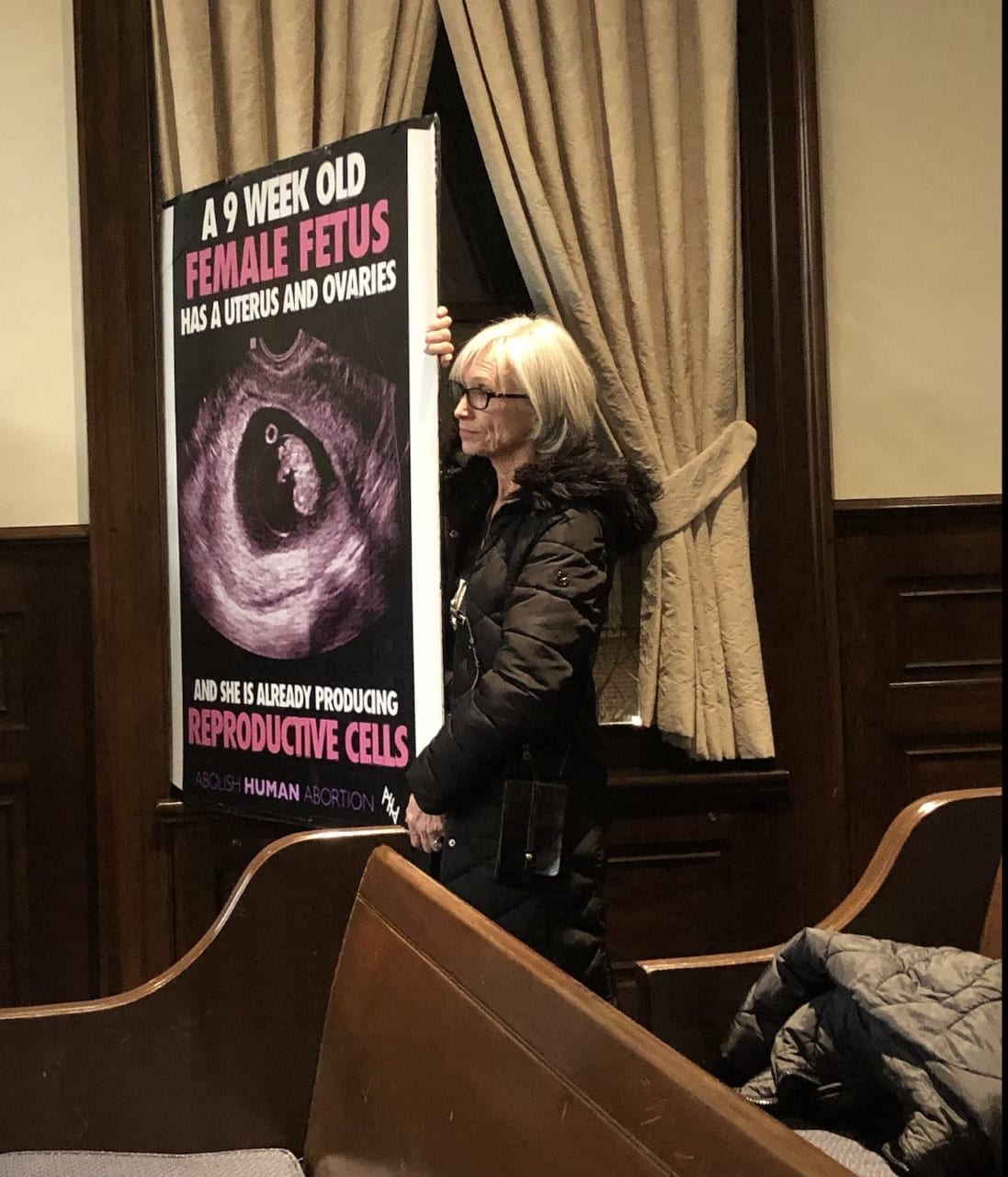 A woman holds up an anti-abortion sign at the Alexandria City Council meeting on March 8, 2022. (Jonathan Darnel)