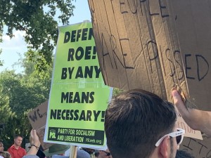 Pro-Abortion supporter with sign from the Party for Socialism and Liberation, one of the organizations present that distributed signs and information to protestors (Hunter Oswald/ The American Spectator)