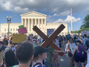 Pro-life demonstrator carries a cross during the Pro-abortion demonstration in front of the Supreme Court causing some of the pro-abortion to verbally assail the pro-life individual (Hunter Oswald/ The American Spectator)