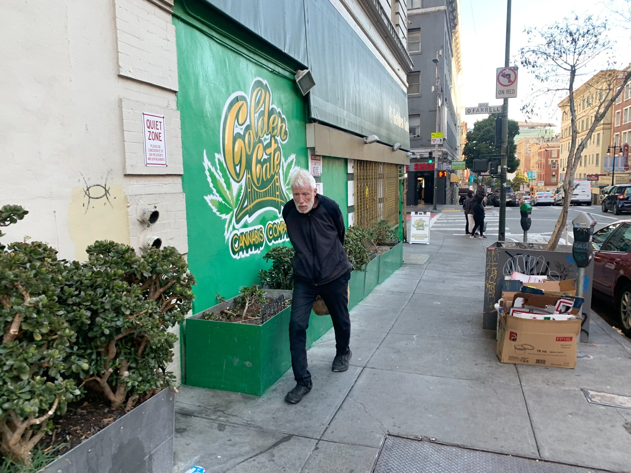 A homeless man walks in from of a cannabis store in San Francisco (The American Spectator)