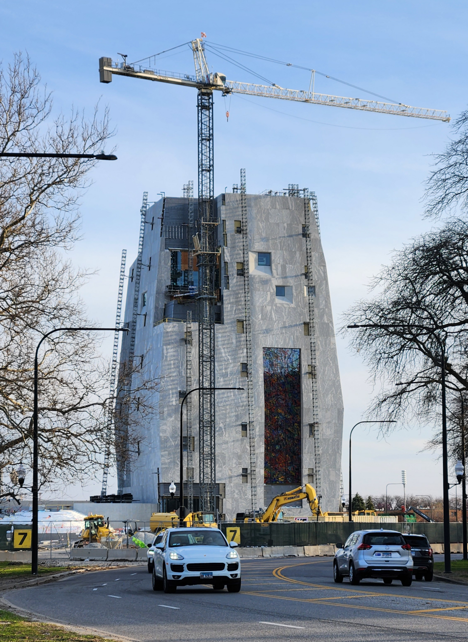 Building under construction with crane and cars nearby.