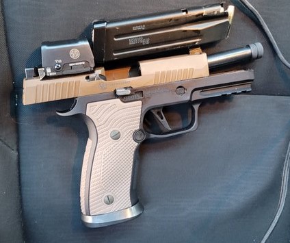 Handgun with scope on dark fabric surface.