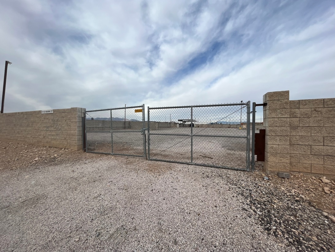 Chain-link gate between tan block walls at an empty lot.